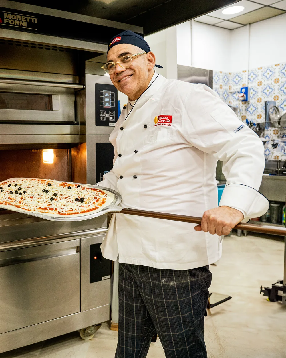 Pizzaiolo che inforna una pizza con la pala davanti al forno