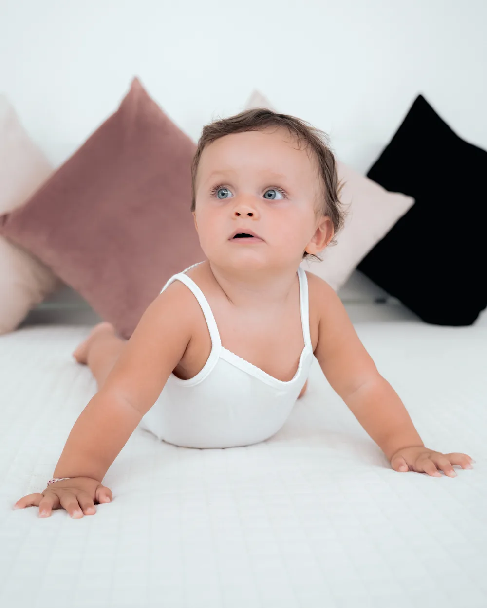 Bambino che gattona su un letto bianco tra i cuscini